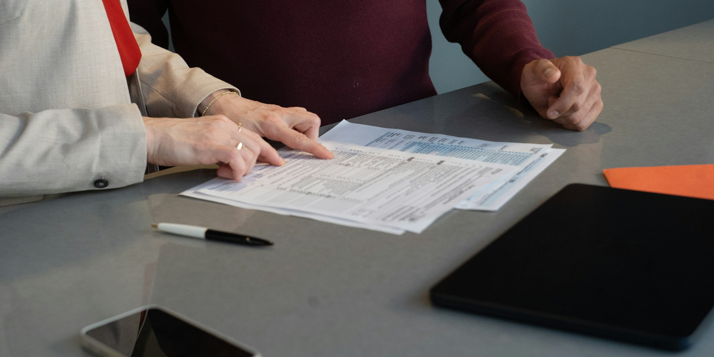 A person reading through printed documents at a table